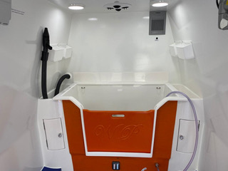 Inside a compact ambulance with a blue floor, displaying medical gear and equipment for patient care.
